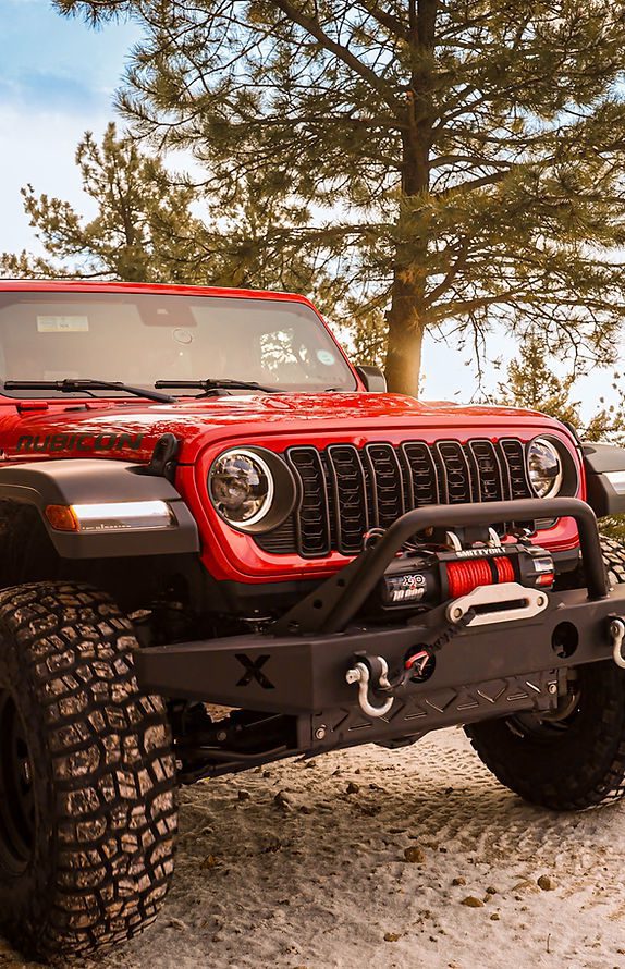 Backbone Adventures - About Our Rentals - Image 2 The front-side view of a red Jeep rental from Backbone Adventures.