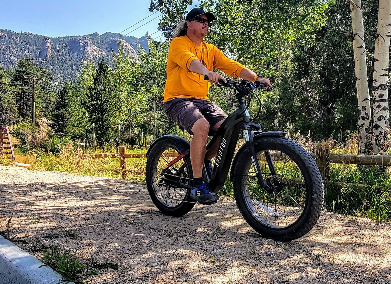 Man with yellow shirt rides an ebike with fat tires in Estes Park, CO.